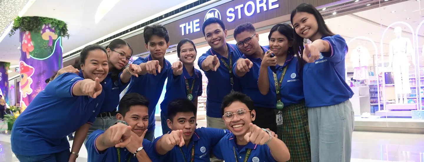 Young people in blue SM Foundation shirts smiling at an SM Store