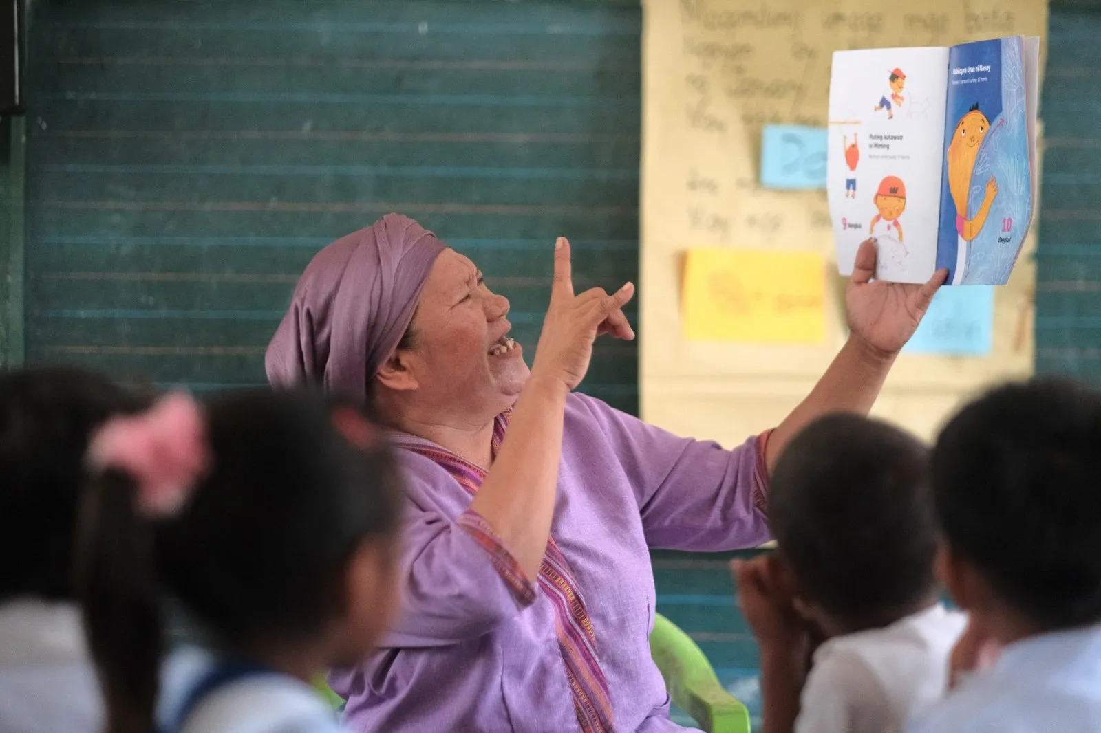 A teacher reads a picture book aloud to young children in a classroom